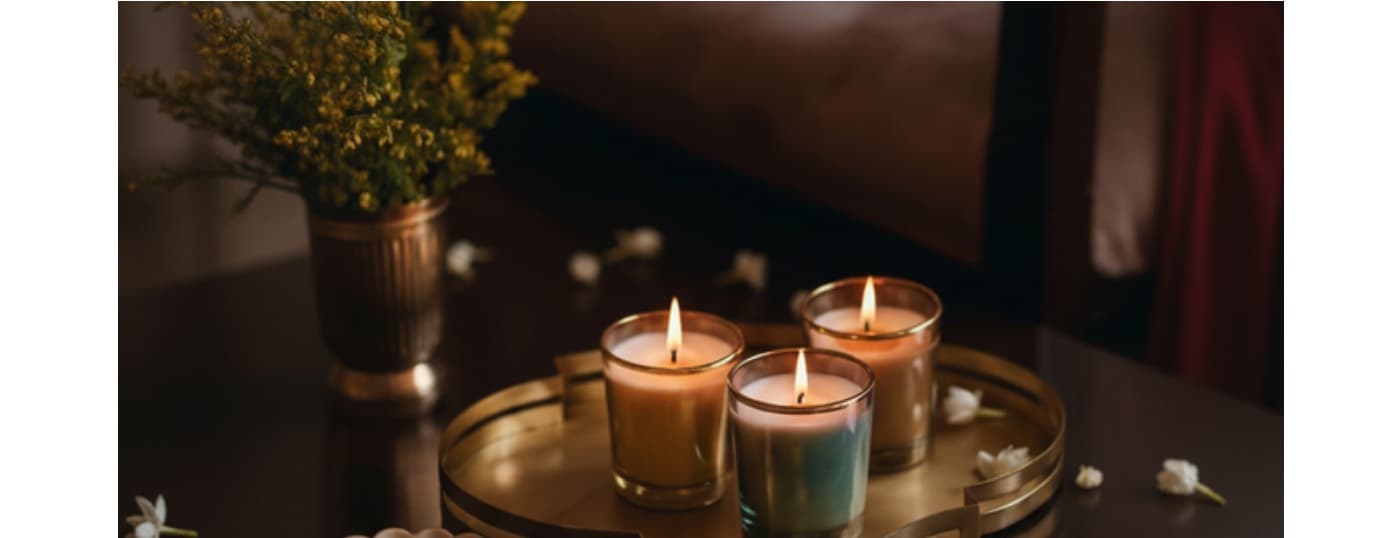 Three lit Wic & Whisper candles on a brass tray with soft florals